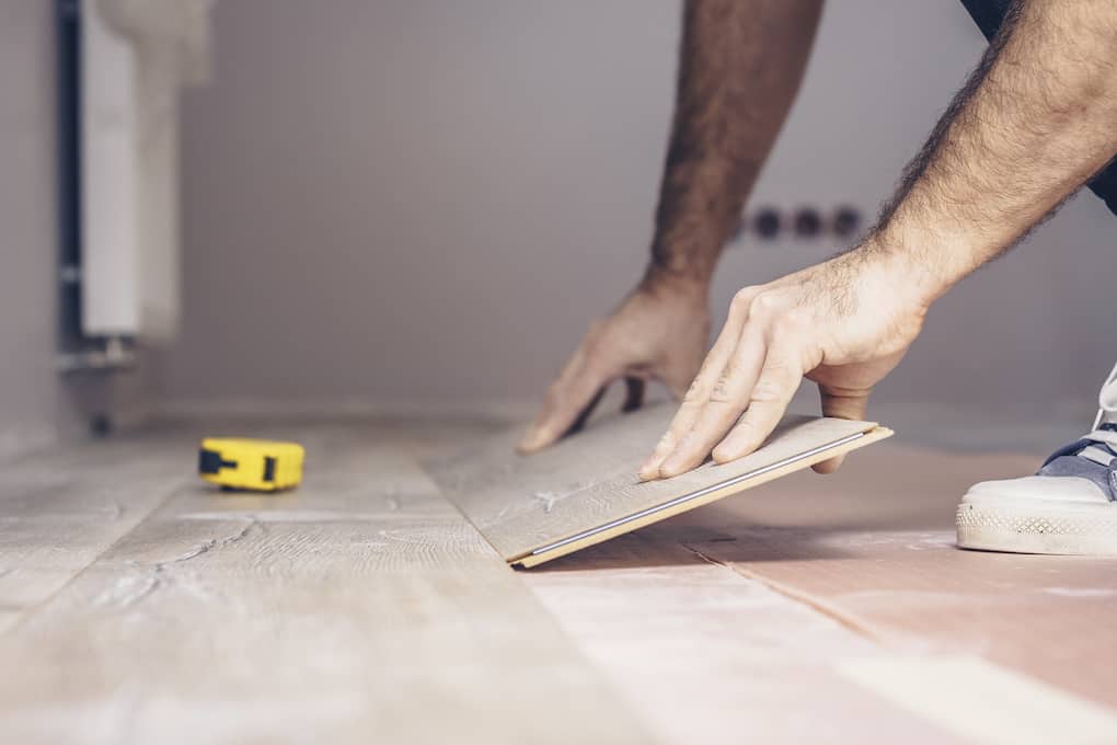 Working with hands installs a laminate board, professional working to insulate a concrete floor