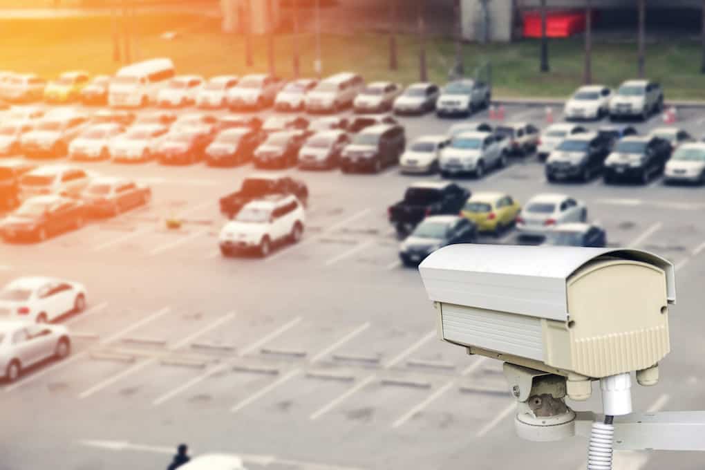 security camera monitoring cars in parking lot that contributes to parking lot costs